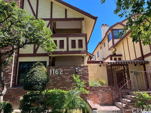 Front view of a multi-story house with a sloped roof and brick detailing.