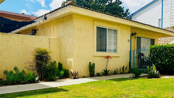 Front view of a single-story house with a yellow exterior and a small gated entrance.