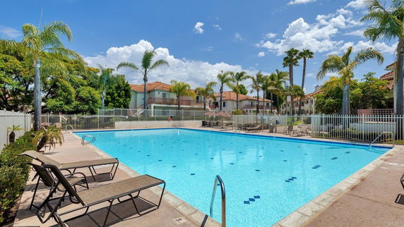 Outdoor swimming pool with lounge chairs and palm trees surrounding it.