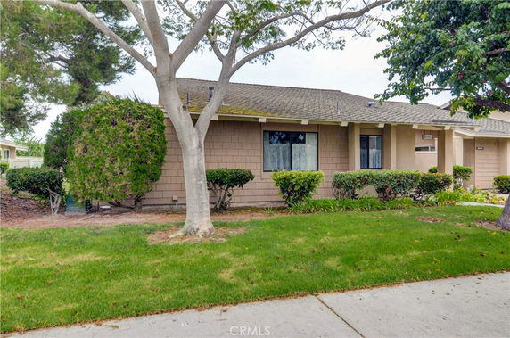 Front view of a single-story house with a shingle roof and a landscaped yard.