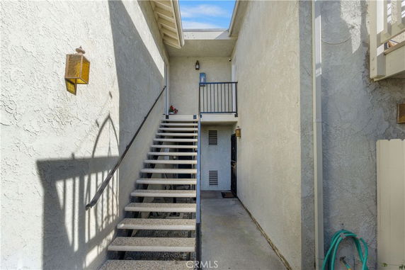 Exterior view of a building entrance with stairs leading to a second-floor doorway.