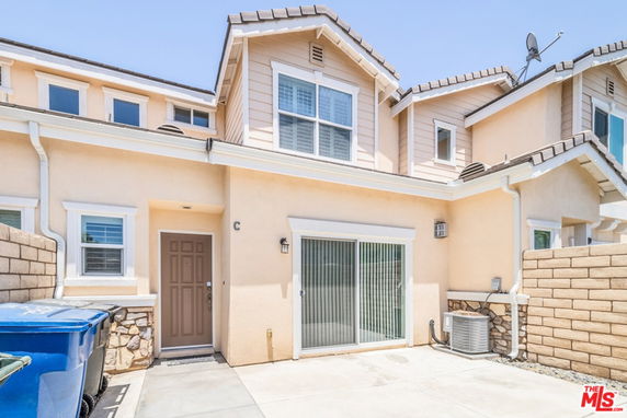 Front view of a two-story house with a sliding glass door and a single entrance door.