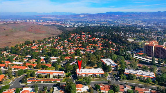 Aerial view of a residential area with clusters of houses, roads, and surrounding landscape.