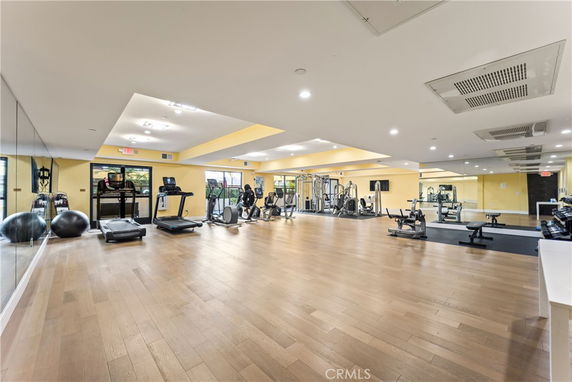 Interior view of a gym with exercise equipment and mirrors on the walls.