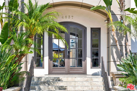 Front view of a house entrance with arched doorway and surrounding greenery.