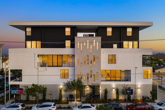 Front view of a modern multi-story building with large windows and a central architectural feature.