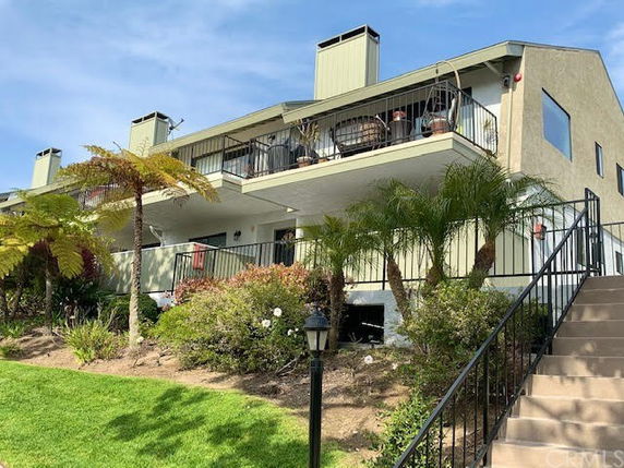 Front view of a multi-story building with balconies and a staircase.
