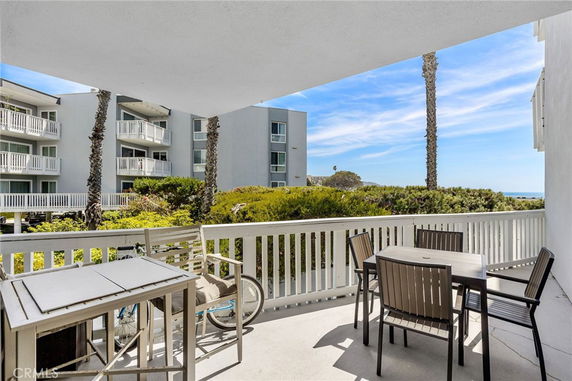 Balcony view overlooking residential buildings and ocean in the distance.