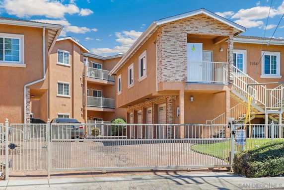 Front view of a multi-story residential building with a gated entrance.