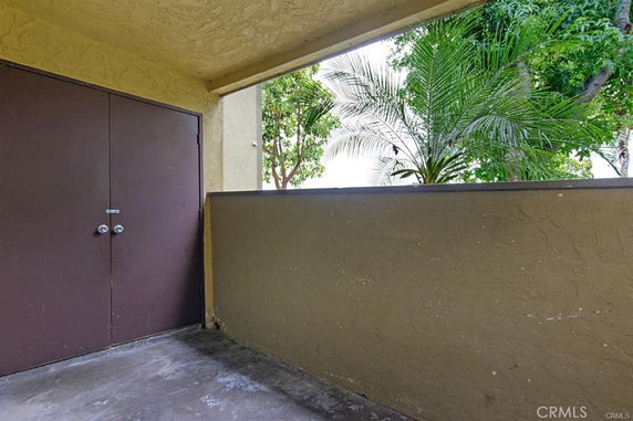 Covered outdoor area with a brown double door and view of trees.