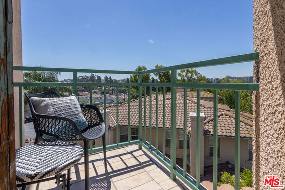 Balcony view overlooking rooftops and distant scenery.