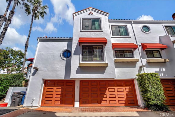 Front view of a multi-story building with orange garage doors and red awnings.