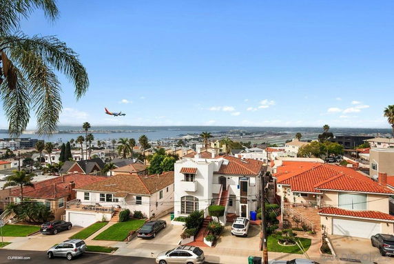 Panoramic view of a residential area with houses and coastal scenery in the background.