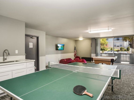 Room with table tennis and pool table, lounge seating, and a TV.
