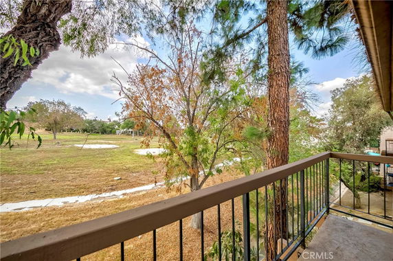 View from a balcony overlooking a grassy field with trees.