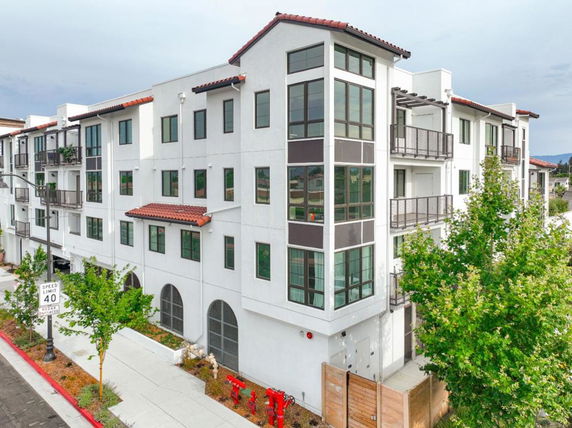 Front view of a multi-story building with balconies and large windows.
