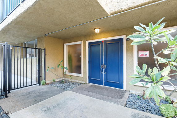 Covered entryway with blue double doors and adjacent windows.