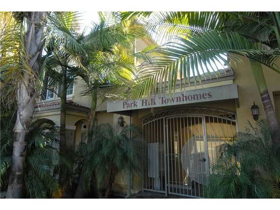 Front view of a townhome entrance with gated entry and palm trees.