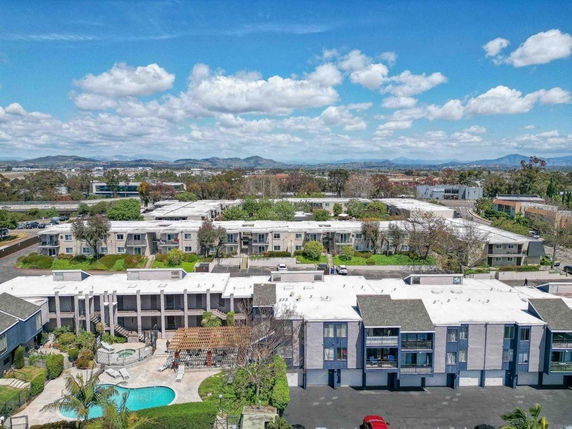 Wide view of a residential complex with surrounding landscape and mountains in the background.