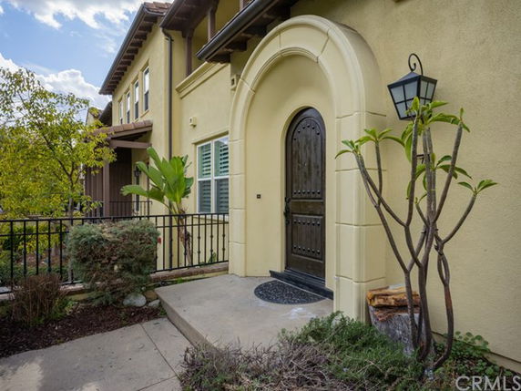 Front view of a two-story house with an arched doorway and a black door.
