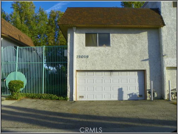 Front view of a building with a garage and a green metal fence.