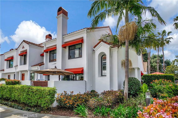 Front view of a two-story house with Mediterranean architectural style, featuring white walls and red roof tiles.