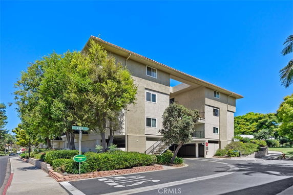 Front view of a multi-story apartment building with a flat roof and balconies.