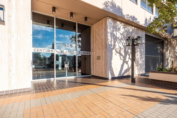 Front view of a building entrance with glass doors and tiled flooring.