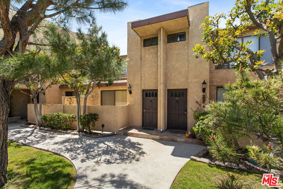 Front view of a two-story townhouse with stucco exterior and double entrance.