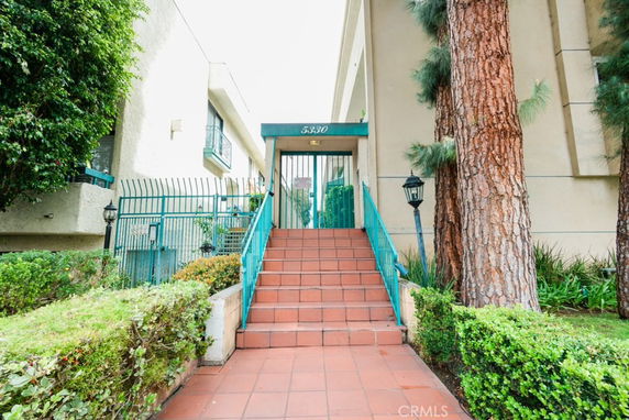 Front view of a building with a gated entrance and steps leading up to it.