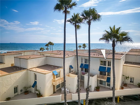 Buildings near the ocean with palm trees and ocean view in the background.