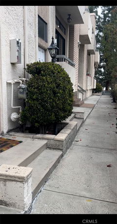 Side view of a multi-story building with steps and a lamp post near the entrance.