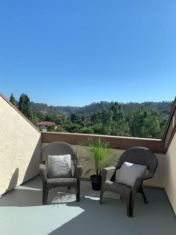 Terrace with outdoor seating and scenic view of hills and trees.