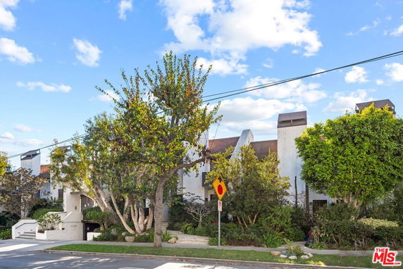 Front view of a multi-story building with a unique architectural design and trees in front.