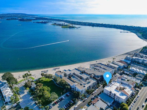 Aerial view of coastal residential area with buildings near a beach and a large body of water.