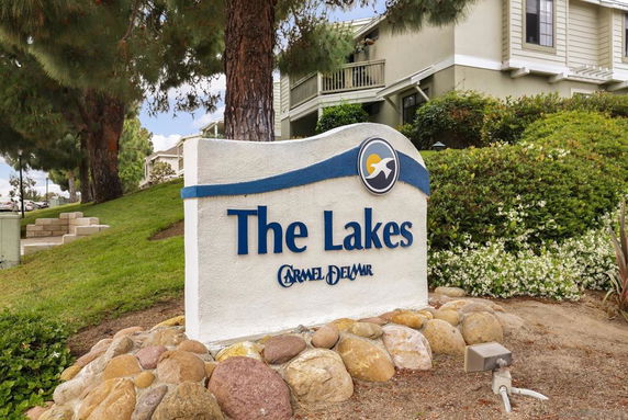 Exterior view of a building complex with landscaping and a large sign labeled 'The Lakes.'