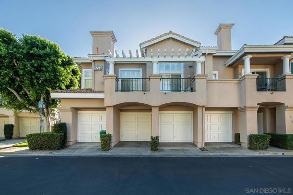 Front view of a multi-story residential building with garages and balconies.