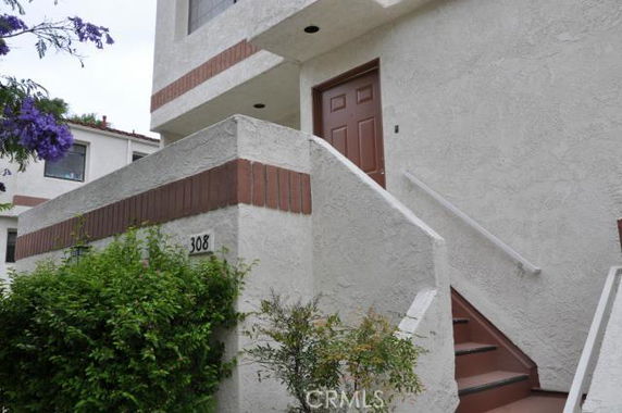 Front view of a residential building with stairs leading to a door.