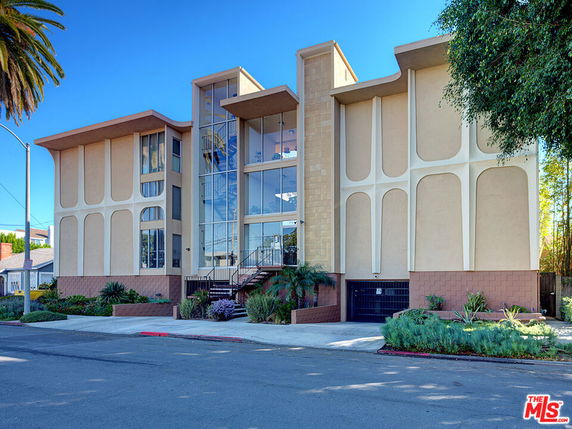 Front view of a multi-story modern building with large glass windows and unique architectural design.