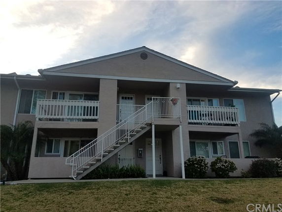 Front view of a two-story residential building with balconies and exterior stairs.