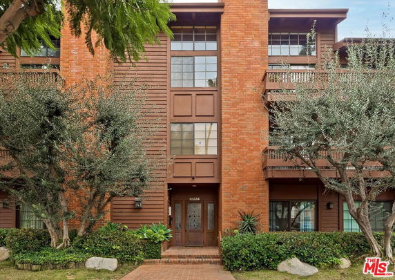 Front view of a multi-story brick and wood building with large windows and balconies.
