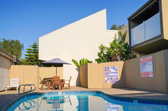 Outdoor swimming pool area with a table and umbrella.