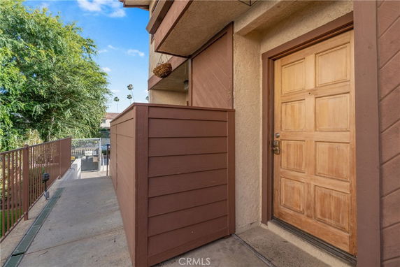 Front view of a building entrance with a wooden door and a brown railing.