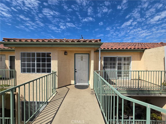 Front view of a multi-unit building with a walkway and iron railing.