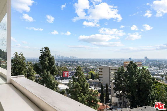 View of a cityscape from a high vantage point with trees and buildings in the foreground.