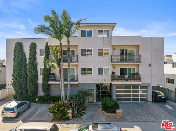 Front view of a multi-story building with balconies and a garage.