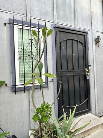 Front view of a house entry with a black door and a barred window.