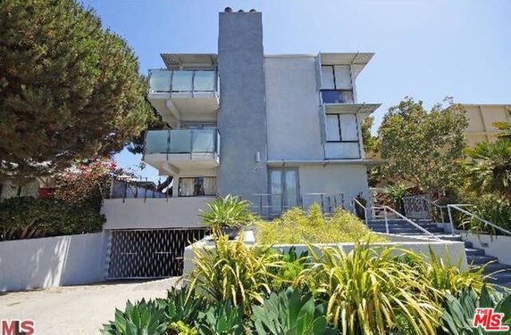 Front view of a modern multi-story building with balconies and a garage entrance.