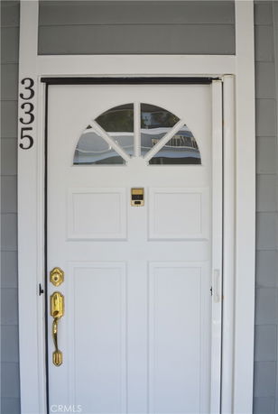Close-up view of a white front door with a half-circle window and gold handle.