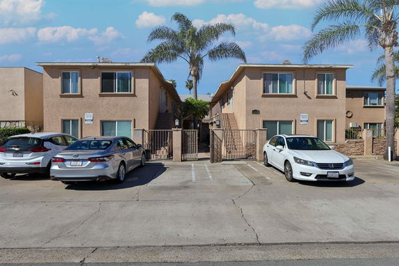 Front view of a two-story apartment building with a parking area in front.